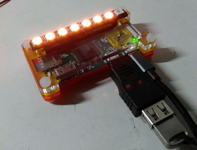 Tails Out a Box Early prototype: a Raspberry Pi Zero in an orange acrylic case with a row of lit LEDs along the top and a USB stick plugged in